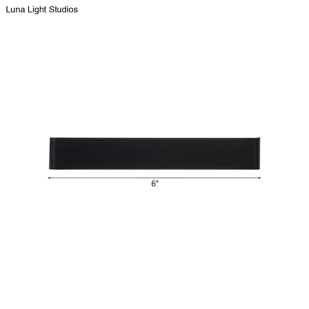 Black rectangular wall lamp 6 inches long with silver accents providing warm white light for living room use