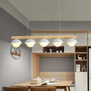 Modern minimalist wood island pendant with natural wood bar and five white grey dome-shaped shades for kitchen island lighting