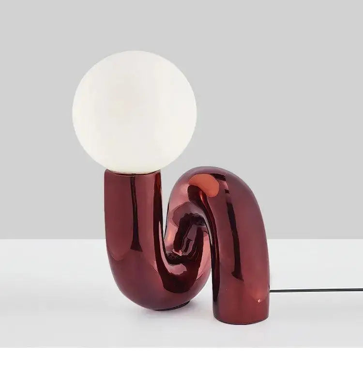 Decorbites™ modern art table lamp with a sleek burgundy s-shaped base and smooth white spherical bulb for stylish lighting