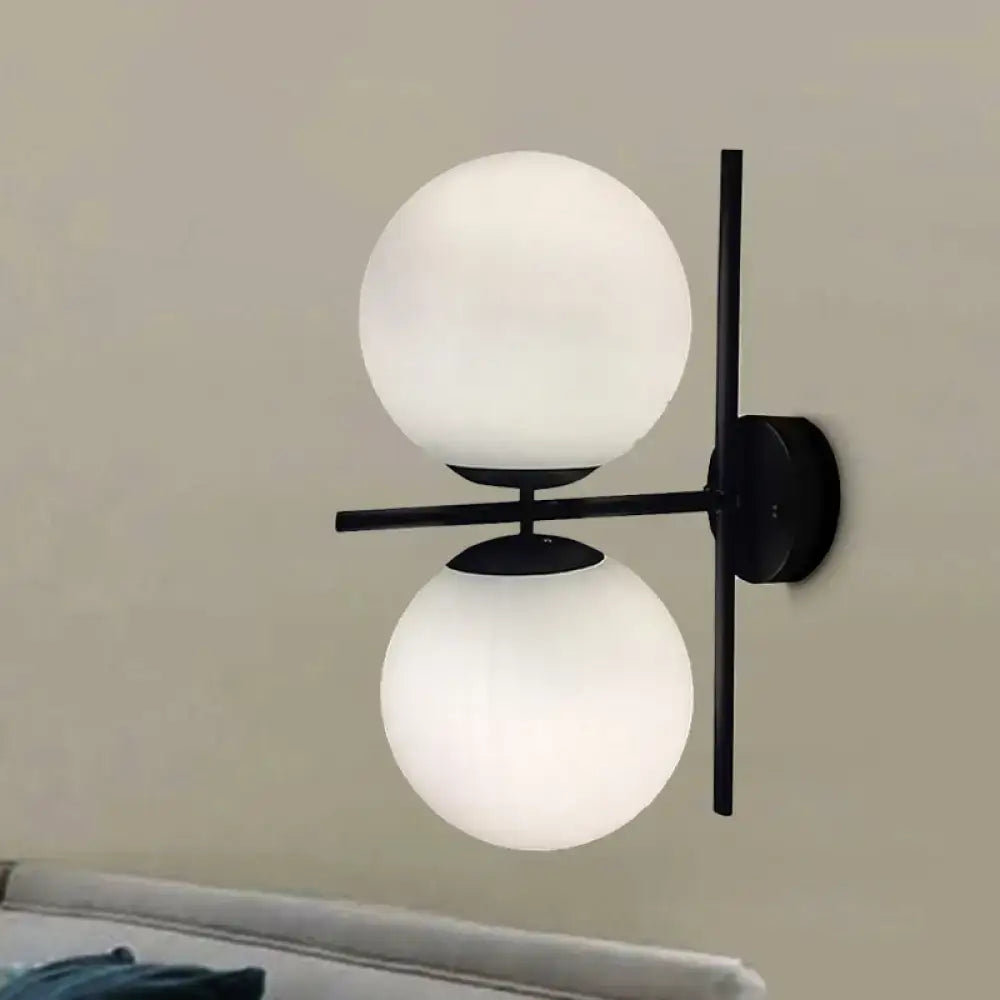 Modern black metal wall light fixture with two frosted white spherical glass shades for living room decor