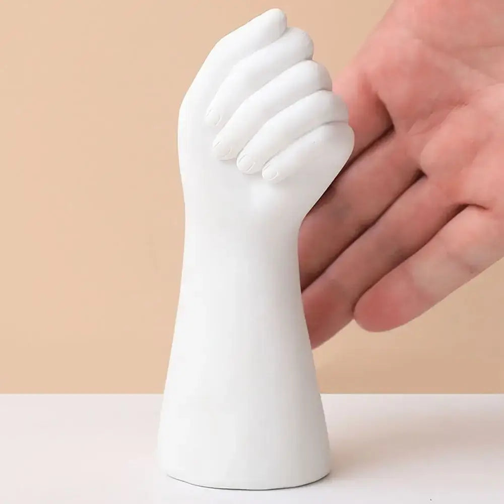 White ceramic arm vase shaped like a hand sculpture with fingers curled into a fist on a flat base by DecorBites™
