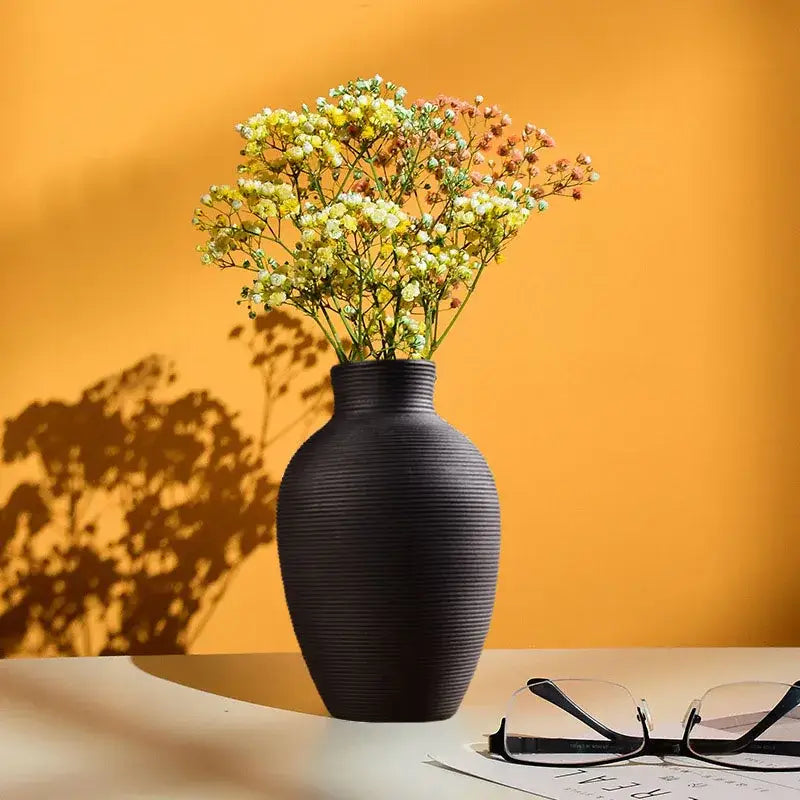 Decorbites modern black ribbed ceramic nordic vase holding yellow and white babys breath for home decor