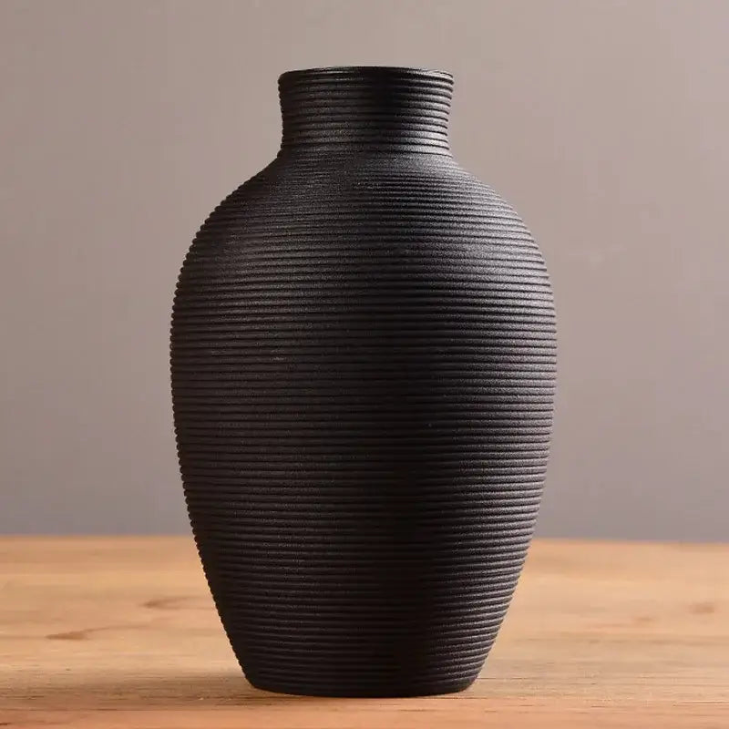A sleek black ceramic nordic vase with a textured ribbed surface and narrow neck for modern home decor