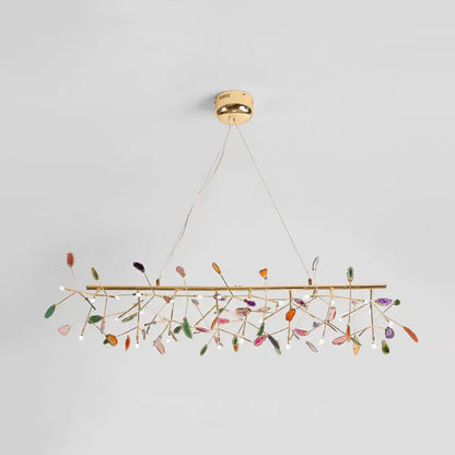 A modern colorful island light fixture with gold metal frame and translucent leaf crystals for warm color temperature