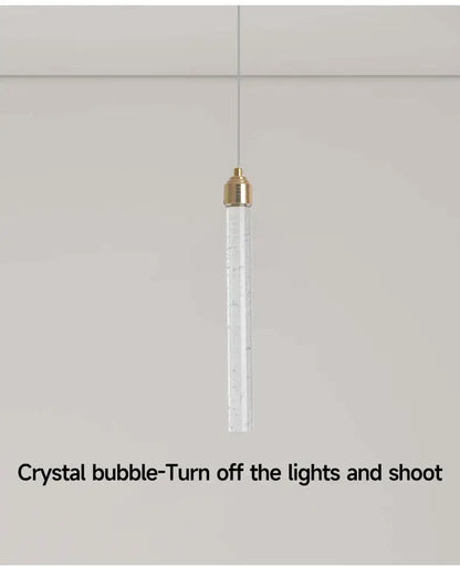 Decorbites modern crystal pendant light featuring a transparent cylinder with gold fixtures and bubble inclusions