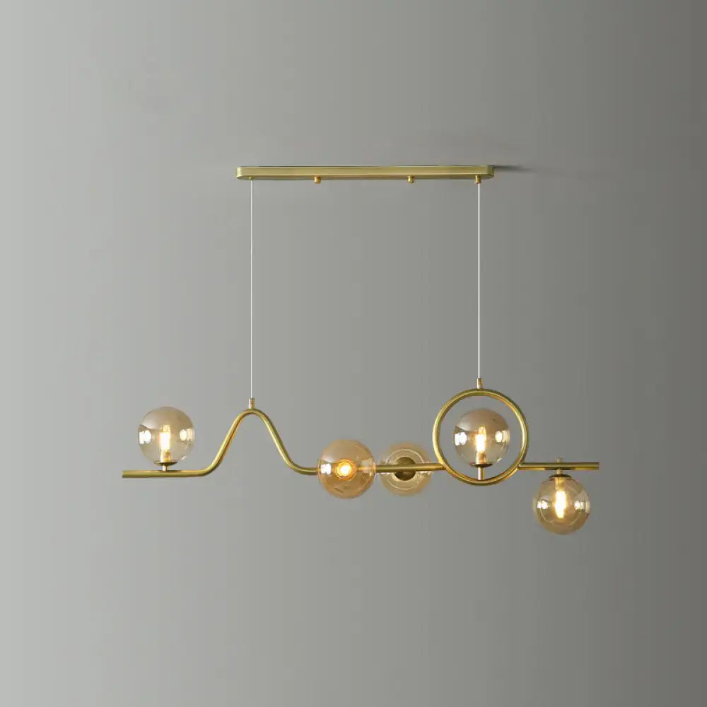 Decorbites modern curve island ceiling light with brass curved arms and amber glass globe bulbs for dining room