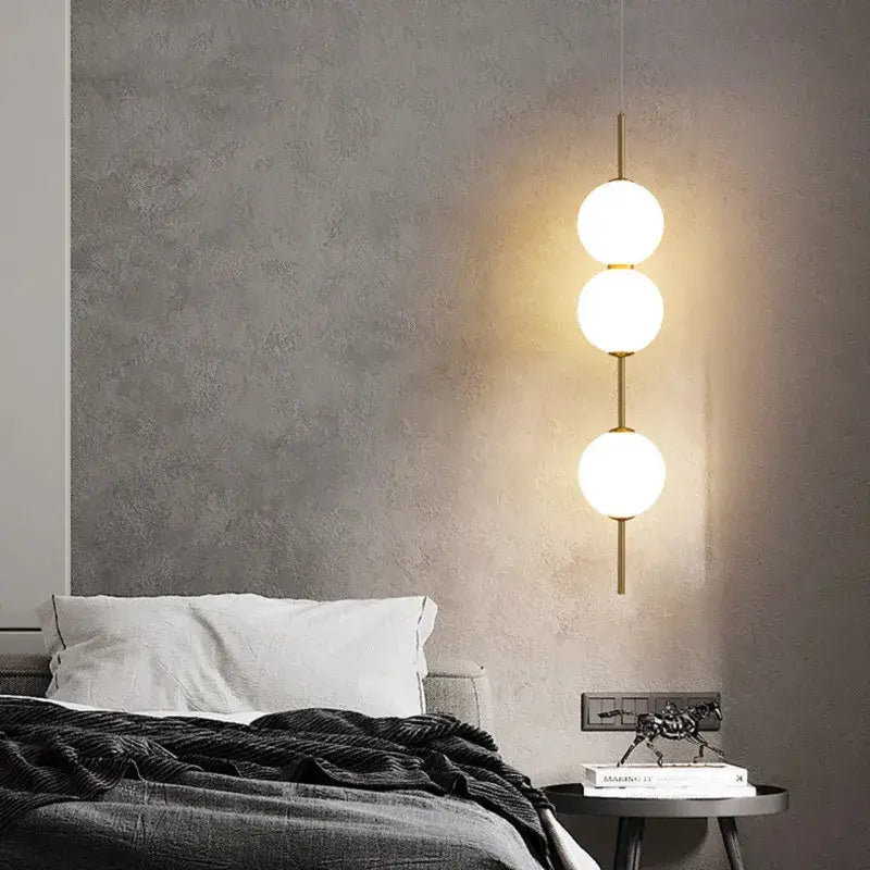 DecorBites™ modern glass pendant lighting with three glowing white spherical bulbs on slender gold-toned rods