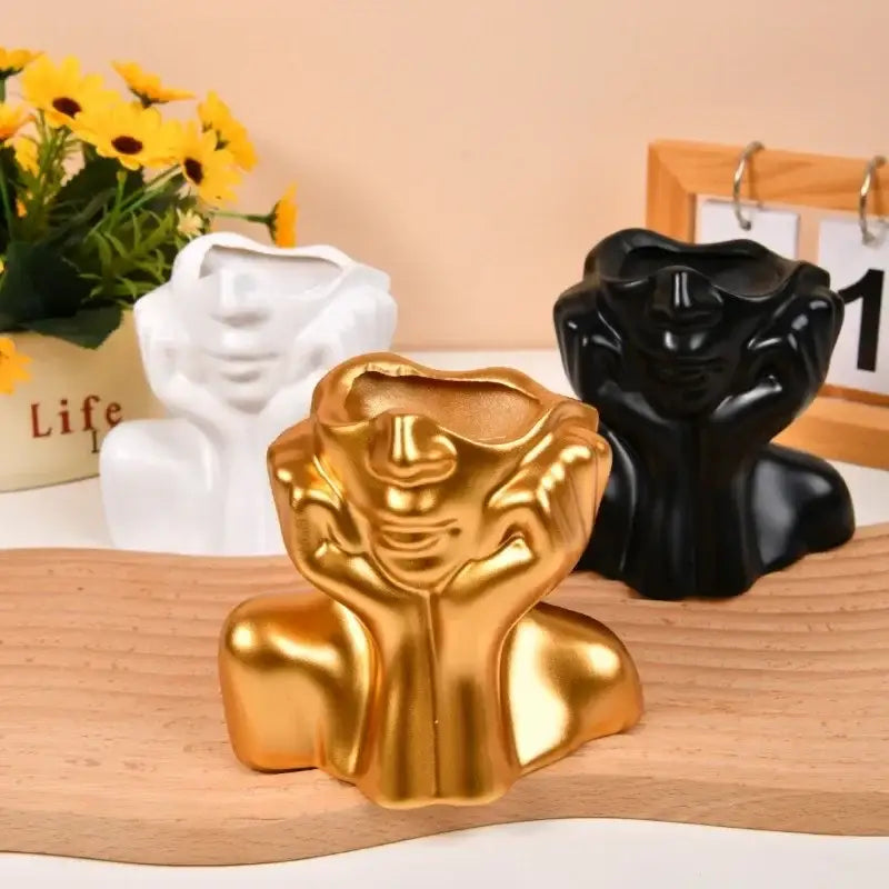 Golden resin vase in a human body shaping design with a smiling face and hands resting on cheeks by decorbites