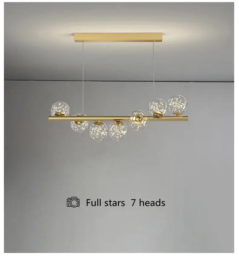 Gold-toned modern pendant led glass chandelier with seven clear globes featuring internal star-like sparkles for dining room