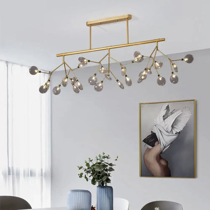 Gold-toned modern metal linear island chandelier with branching arms and frosted glass globe bulbs by DecorBites