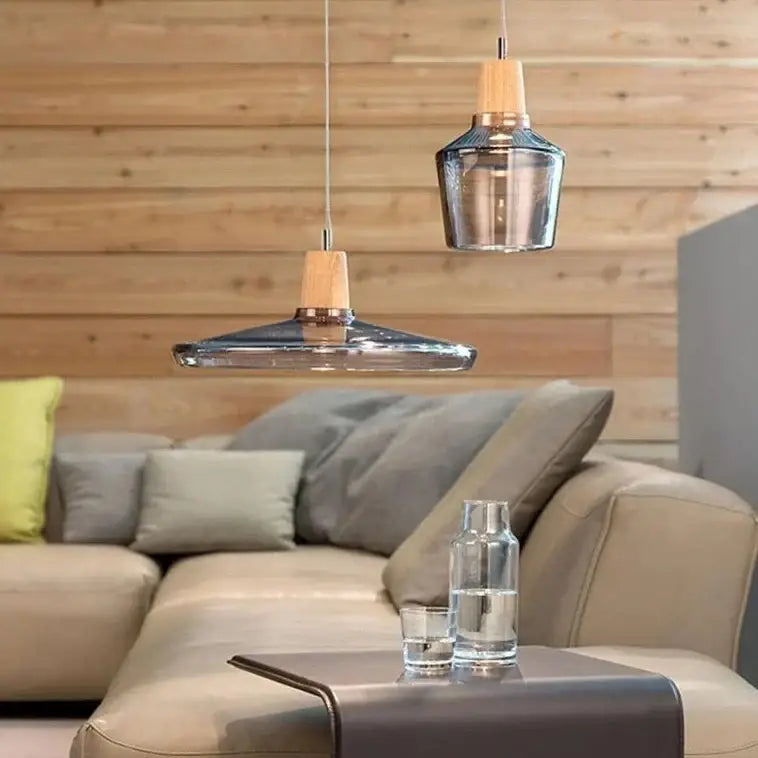 Two modern pendant light fixtures with clear glass light shades and light wood accents above a living room sofa