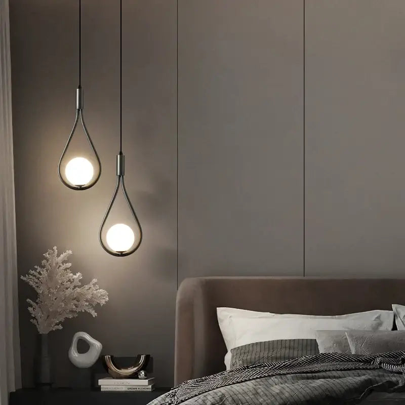 Two DecorBites™ modern nordic pendant lights with teardrop glass shades and black metal frames hanging against dark wall