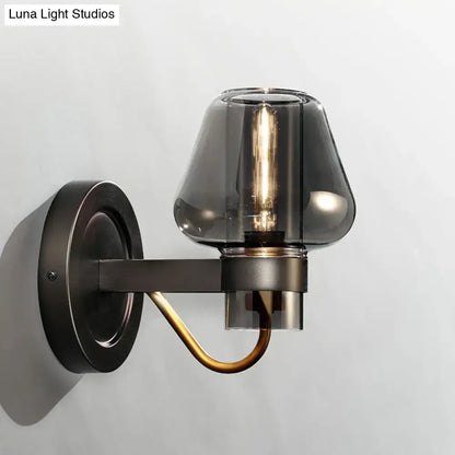 Dark bronze wall sconce with modern smoked glass mushroom shade and brass accent lighting fixture for bedroom use