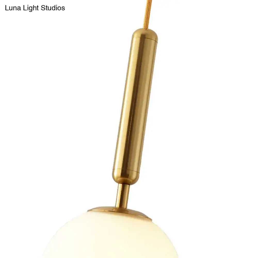 Decorbites modernist white glass pendant light with gold finish featuring a brushed brass cylindrical fixture and frosted globe