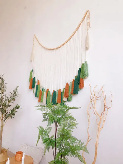 A moroccan bohemian wall decor tapestry featuring a curved wooden bead arch with white green and orange tassels