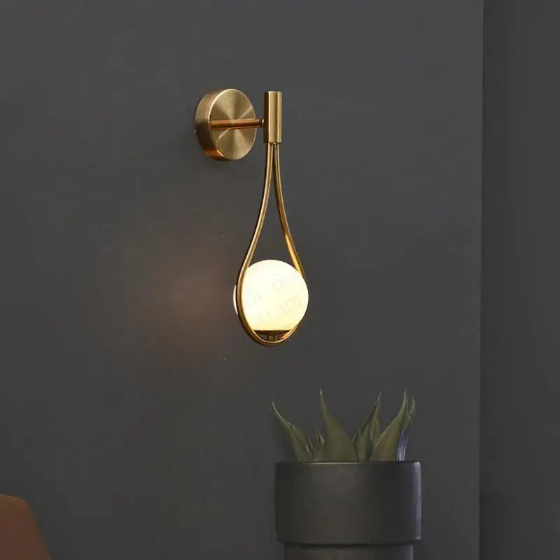 Gold-toned DecorBites™ Moroccan gold modern nordic wall lamp with teardrop frame and glowing frosted glass globe