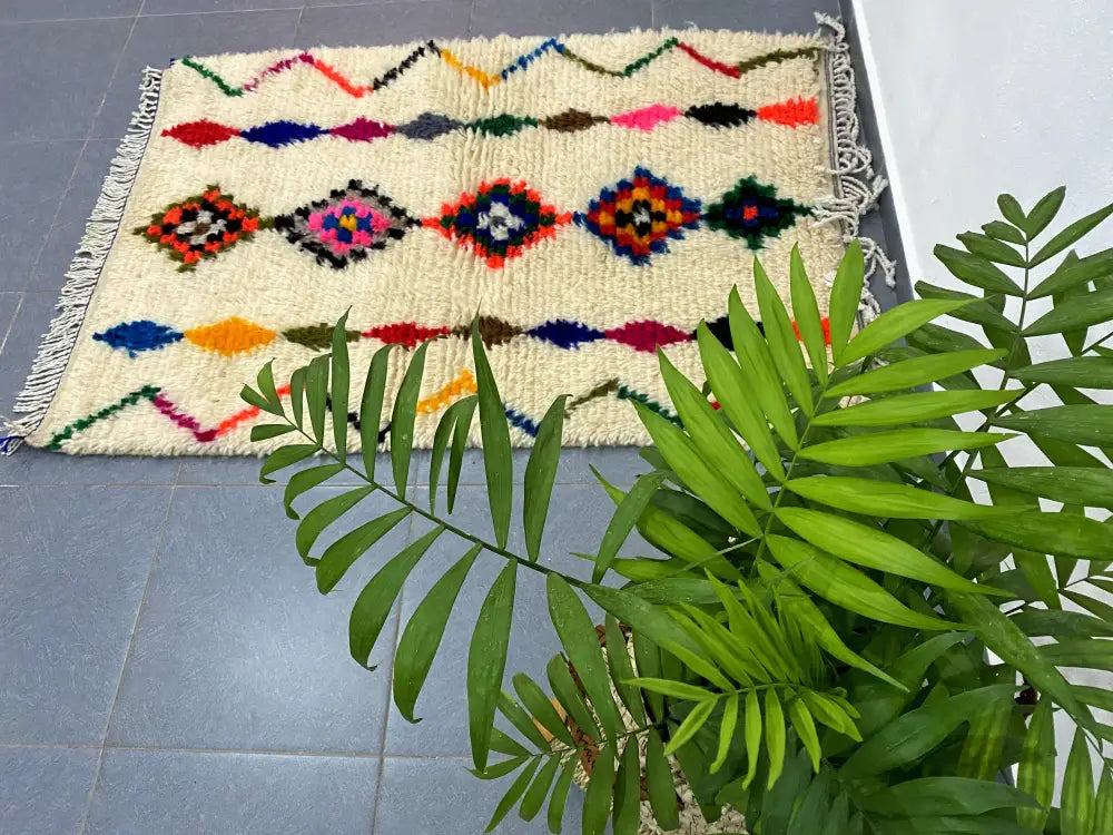 Cream-colored moroccan handmade azilal rug with vibrant pink blue orange and green geometric patterns 1.5m x 1m