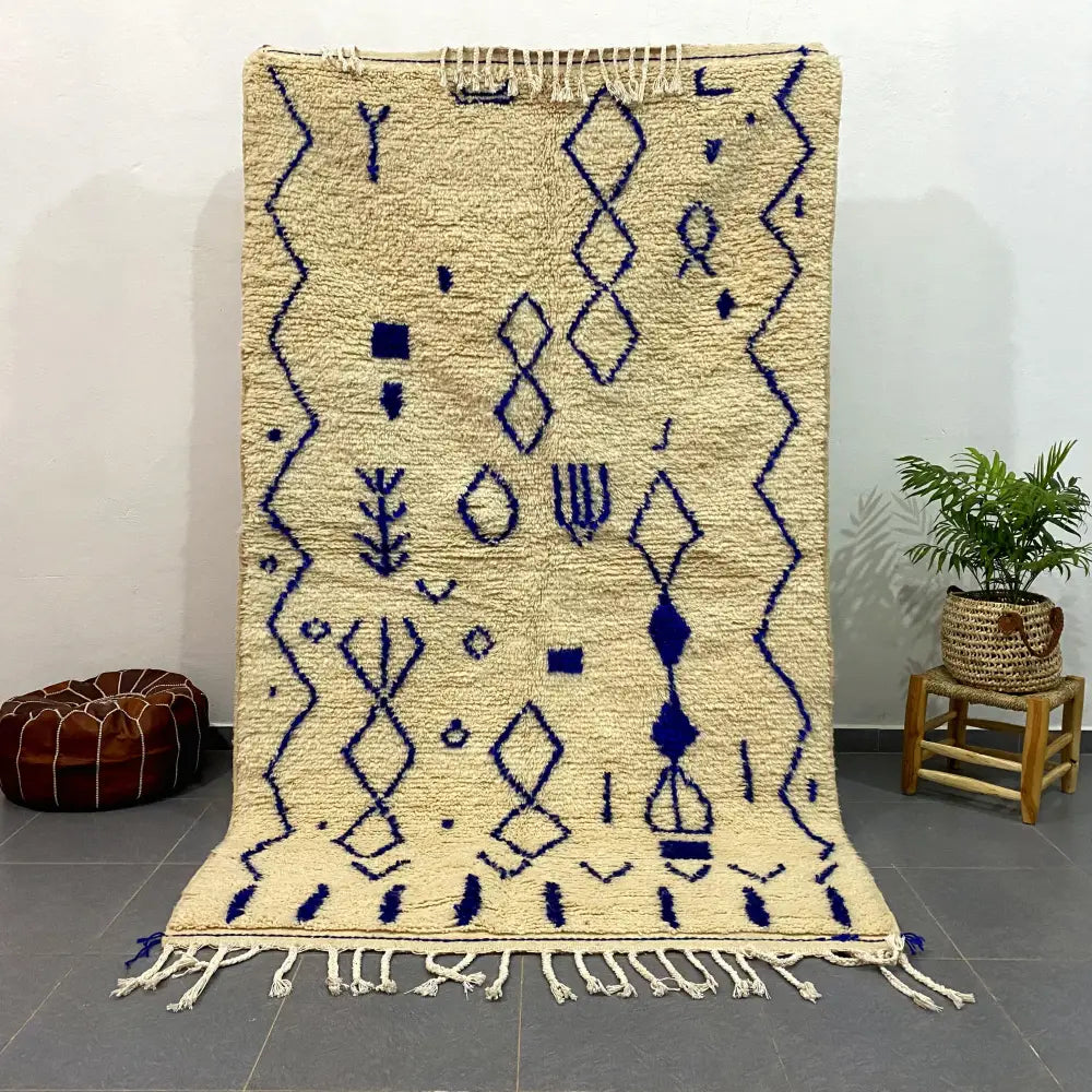 Beige moroccan handmade azilal rug with intricate navy blue geometric patterns and fringed edges by DecorBites™