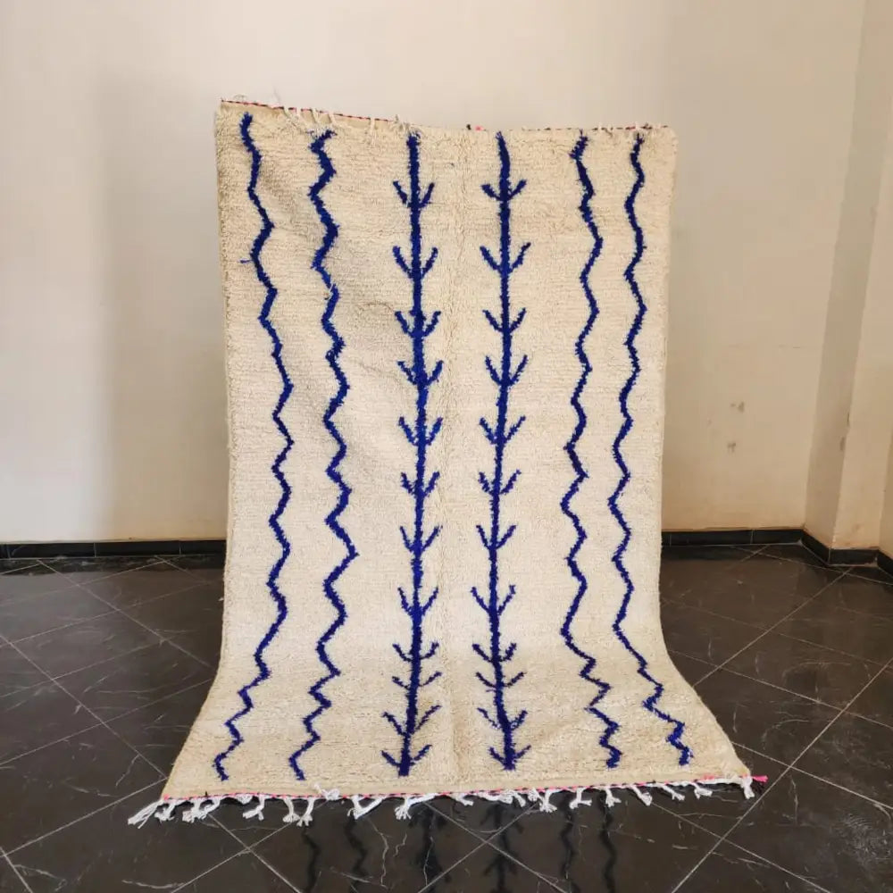 Cream-colored moroccan handmade azilal rug with bold blue zigzag and tree-like patterns and fringed edge 2.5m x 1.5m