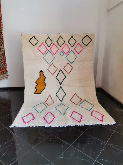 Beige moroccan handmade azilal berber carpet with colorful geometric patterns and central orange motif support sustainable practices