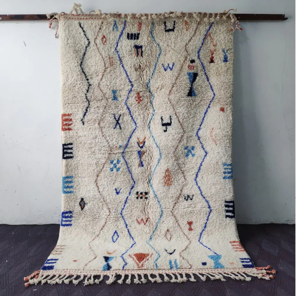 Beige moroccan handmade beni ouarain rug with blue black and orange geometric patterns and fringed edges 2.5m x 1.5m
