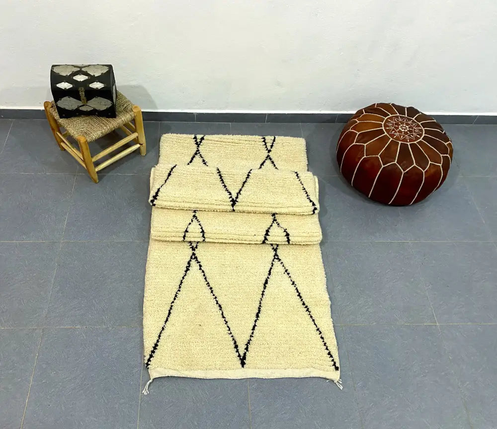 Cream-colored moroccan handmade beni ouarain rug with black geometric zigzag patterns and fringed edges 2.8m x 0.7m