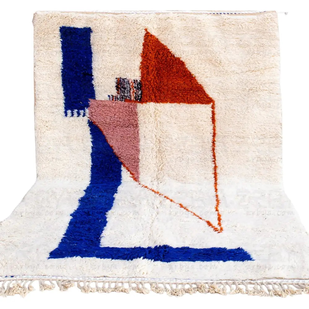 A plush off-white moroccan handmade beni ouarain rug with bold blue terracotta and pink geometric shapes and fringed edges