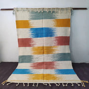 A colorful moroccan handmade custom hanbel rug with horizontal stripes in cream mustard teal and terracotta red with fringed edges