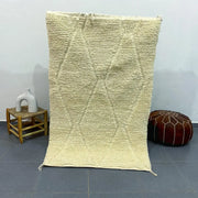 Cream-colored moroccan handmade beni ouarain rug with raised diamond pattern and fringed edges 1.5m x 1m