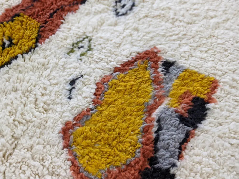 A moroccan handmade traditional azilal carpet with a plush cream base and yellow terracotta gray abstract patterns