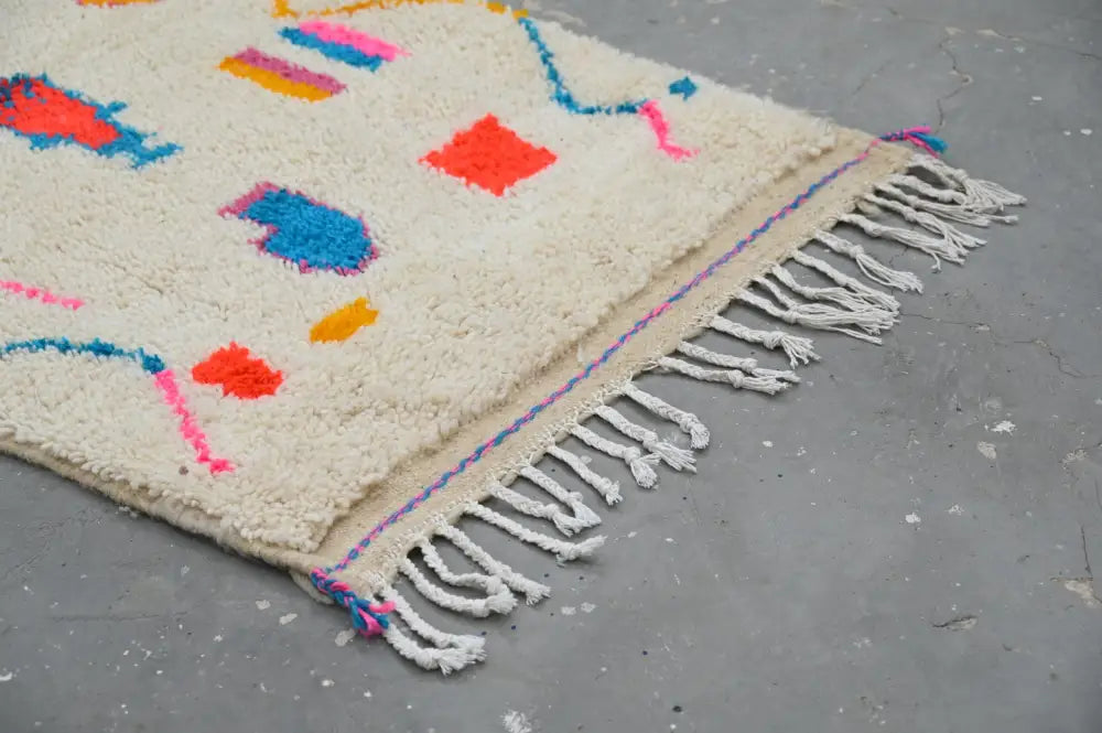 Cream-colored moroccan handmade azilal hallway rug with vibrant geometric patterns and fringed edge by decorbites