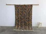 A moroccan handmade azilal rug by decorbites with dark brown base geometric patterns in orange yellow black pure natural wool