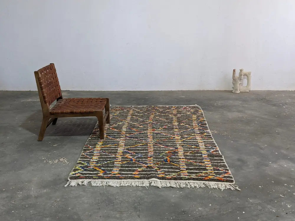 Rectangular moroccan handmade azilal rug in pure natural wool with dark base and vibrant geometric patterns with fringed edges
