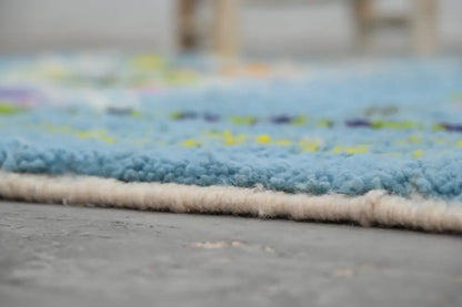 A soft blue shaggy moroccan handmade traditional azilal rug with cream border and yellow, purple, green accents