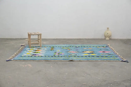 A vibrant blue DecorBites™ moroccan handmade traditional Azilal rug with colorful geometric patterns and fringed edges