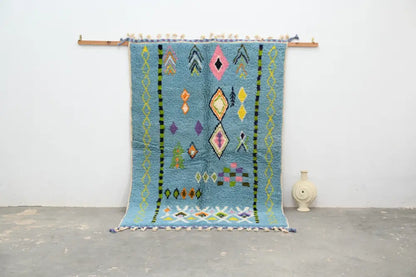 A vibrant blue moroccan handmade traditional azilal rug with colorful geometric patterns and tassels by decorbites