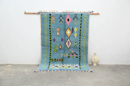 A vibrant blue moroccan handmade traditional azilal rug with colorful geometric patterns and tassels by decorbites