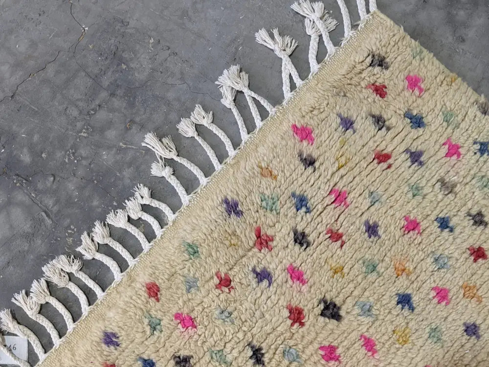Beige moroccan handmade azilal rug with colorful hand-knotted star patterns and white fringe in pure natural wool