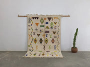 Beige moroccan handmade traditional azilal rug with black yellow green and orange geometric patterns on textured wool base