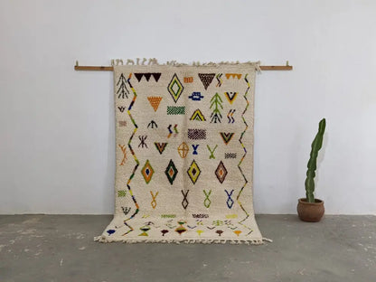 Beige moroccan handmade traditional azilal rug with black yellow green and orange geometric patterns on textured wool base