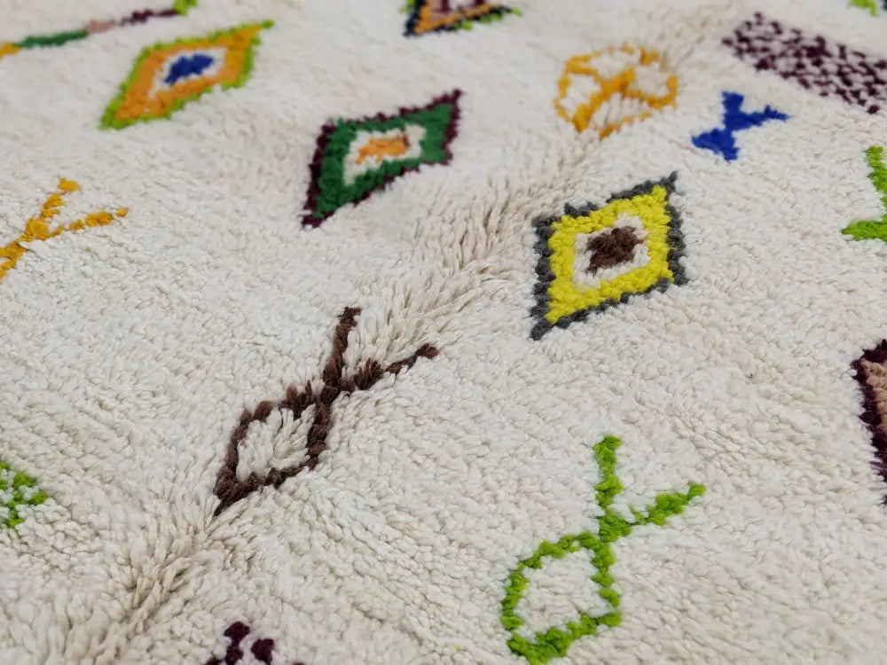 Cream-colored moroccan handmade traditional azilal rug with plush texture and vibrant geometric patterns by DecorBites