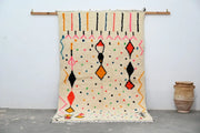Cream-colored moroccan handmade traditional azilal rug with vibrant orange red black pink and blue geometric patterns