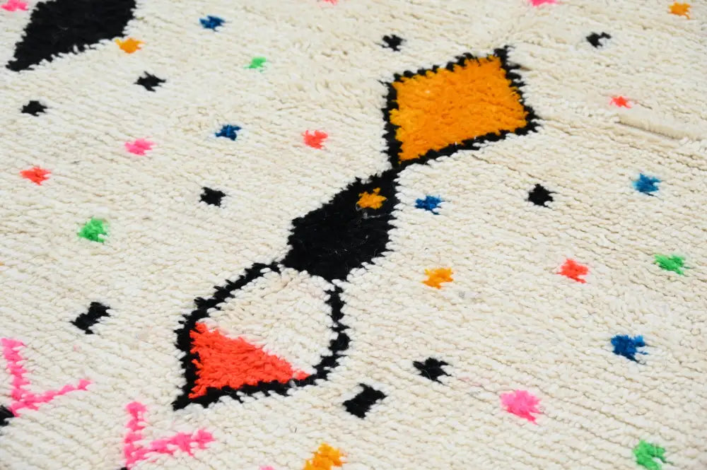 Cream-colored moroccan handmade traditional azilal rug with bold black orange red geometric patterns and colorful dots
