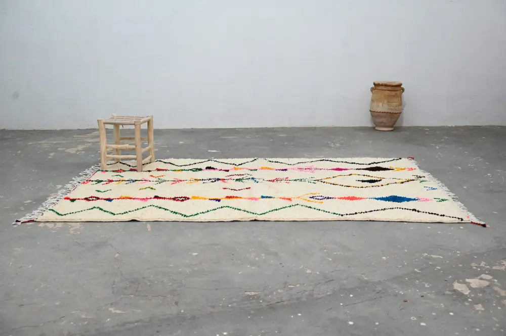 Cream-colored moroccan handmade traditional azilal rug with vibrant multicolored geometric patterns and fringed edges
