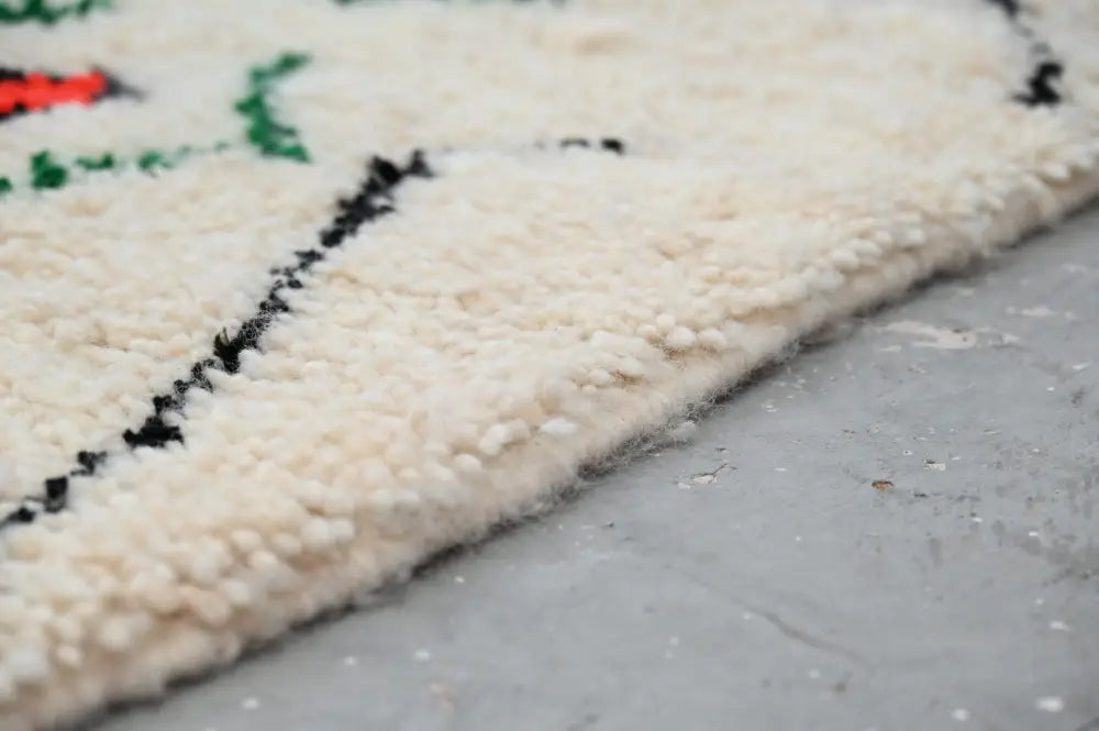Cream-colored plush wool moroccan handmade traditional azilal rug with bold black and green geometric patterns