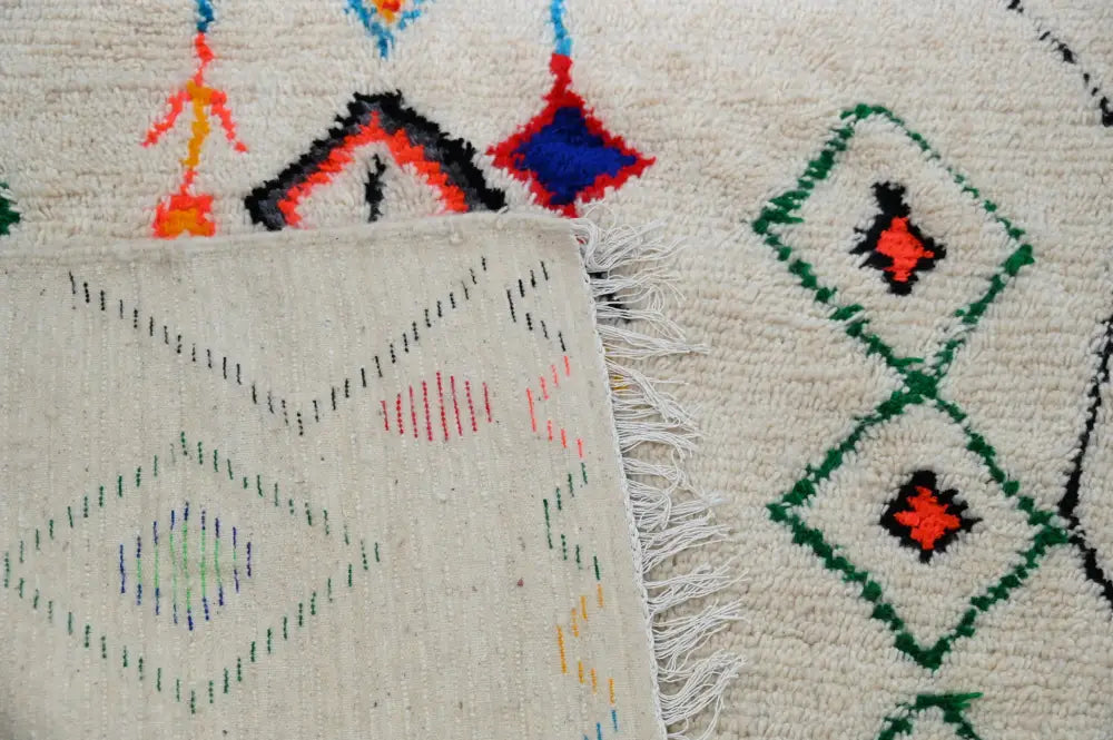 Cream-colored moroccan handmade traditional azilal rug with intricate geometric patterns and fringed edges by decorbites