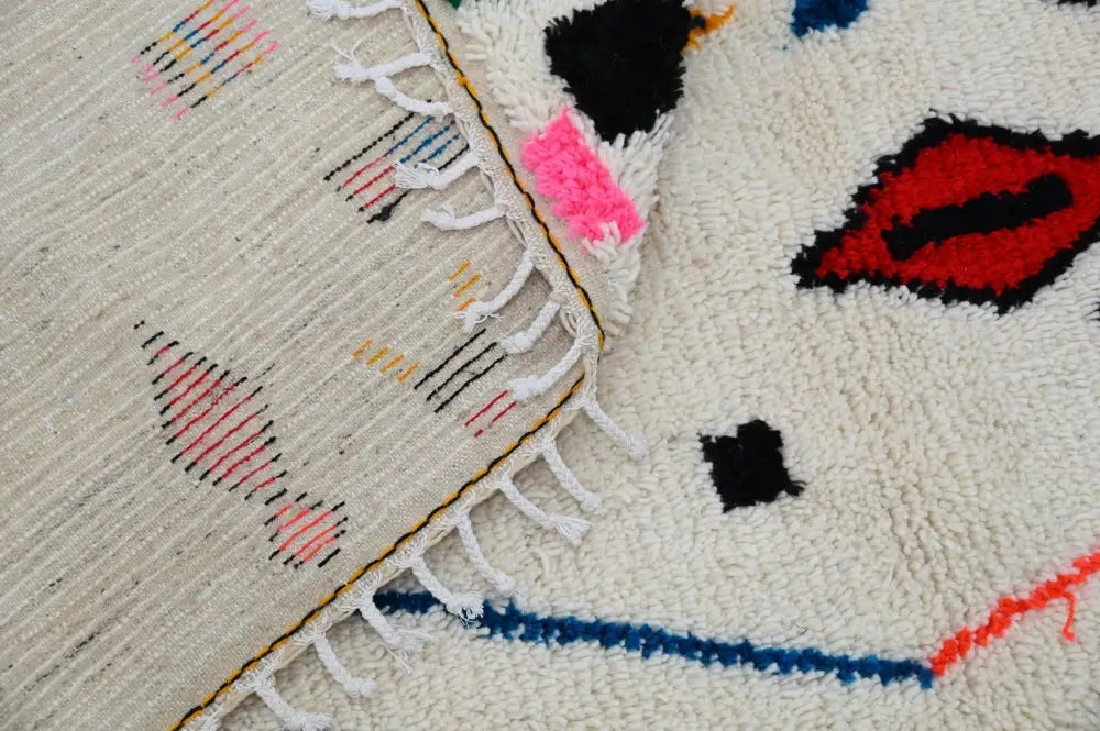 A cream-colored moroccan handmade traditional azilal rug with bold abstract geometric patterns and fringed edges