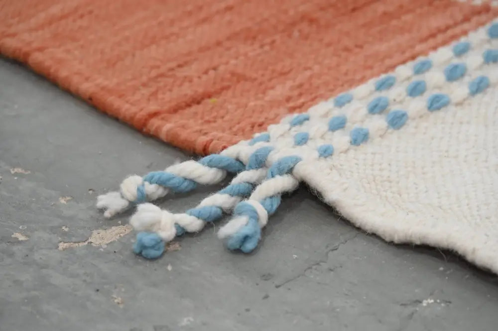 DecorBites™ moroccan handmade traditional azilal rug with coral body, white border, blue dot accents, and braided tassels