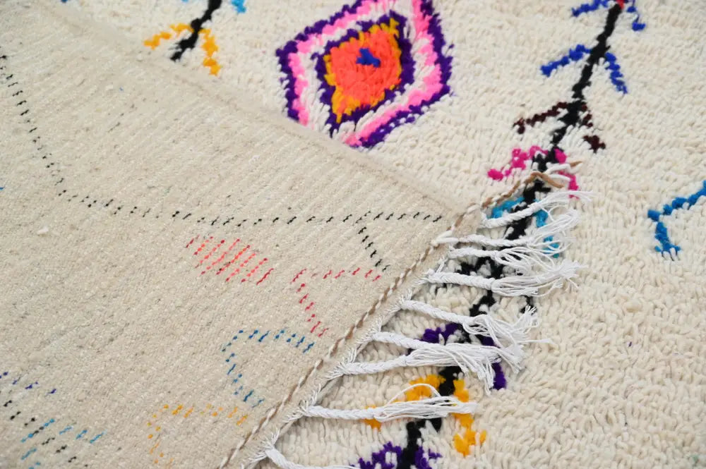 Beige moroccan handmade traditional azilal rug with vibrant pink orange purple and blue geometric patterns and fringed edge