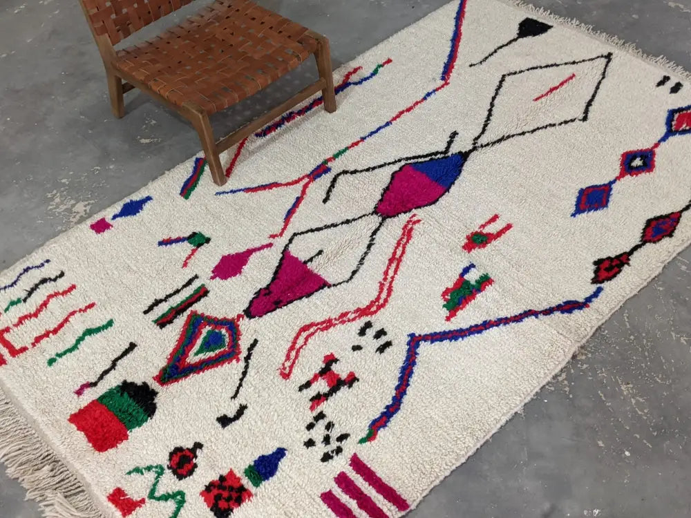 A vibrant cream-colored moroccan handmade azilal rug with bold geometric patterns in pure natural wool